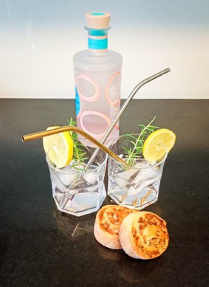 A bottle of gin, two glasses and two rhubarb buns.